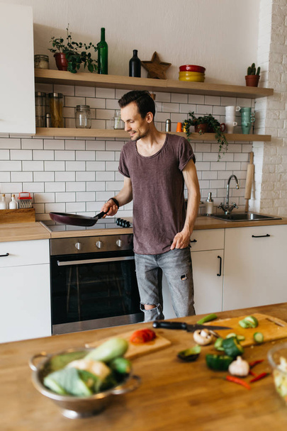 Image of man with frying pan in hands in kitchen - Фото, изображение
