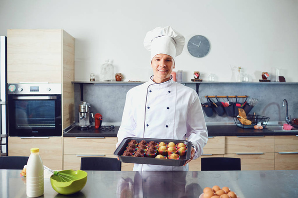 A confectioner prepares cupcakes in the kitchen. - Foto, Bild