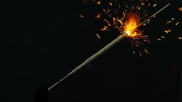 Bengallichter. ein bengalisches Feuer, das sich auf der Diagonale eines Rahmens befindet, entzündet eine orangefarbene Glut. Funken fliegen in verschiedene Richtungen auseinander. aufgenommen auf schwarzem Hintergrund, kann in Ihrem Video verwendet werden ein - Filmmaterial, Video