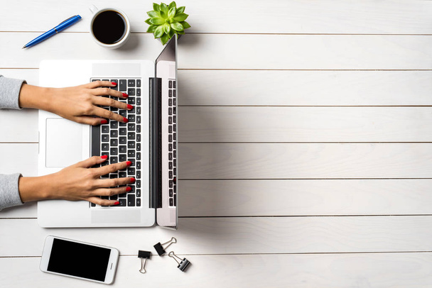 Female hands working on modern laptop. White wooden office desktop - Fotografie, Obrázek
