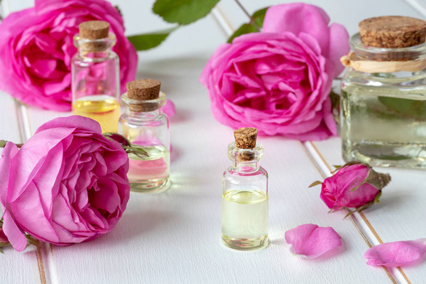 Бутылка эфирного масла со свежими розами - Фото, изображение