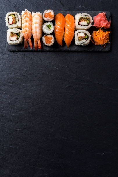 Overhead shot of Japanese sushi on black concrete background - Фото, изображение