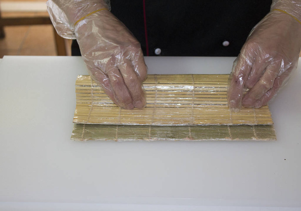 Koch macht Sushi-Rolle mit Bambusmatte - Foto, Bild