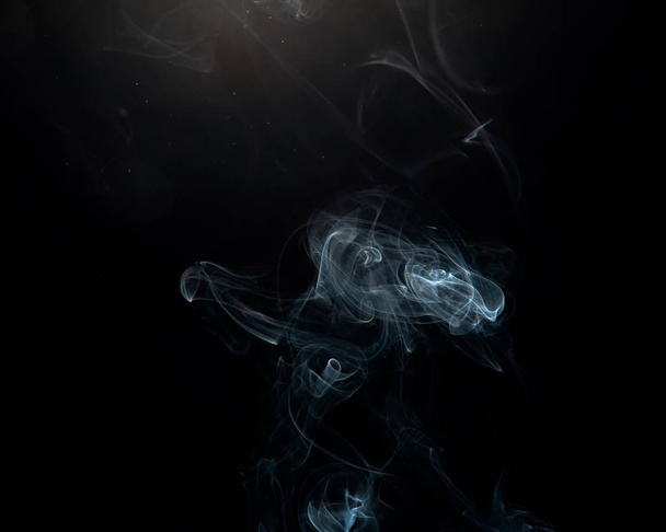 Wispy smoke and fine floating particles over a dark background with a slight lens flare. - Фото, зображення