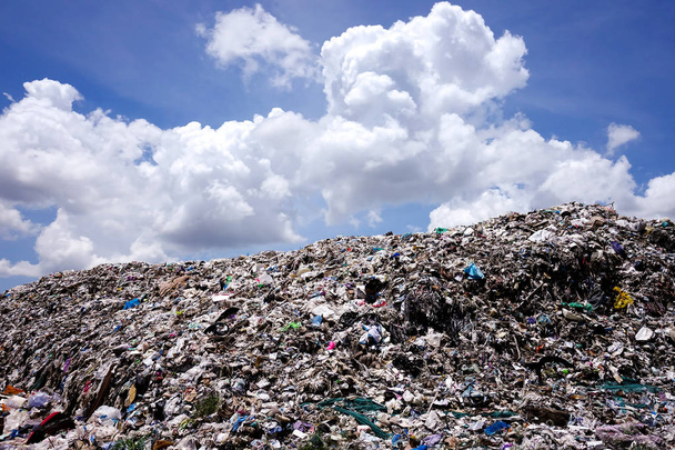 Landfill with blue sky and cumulus clouds, garbage dump in the nature - Photo, Image