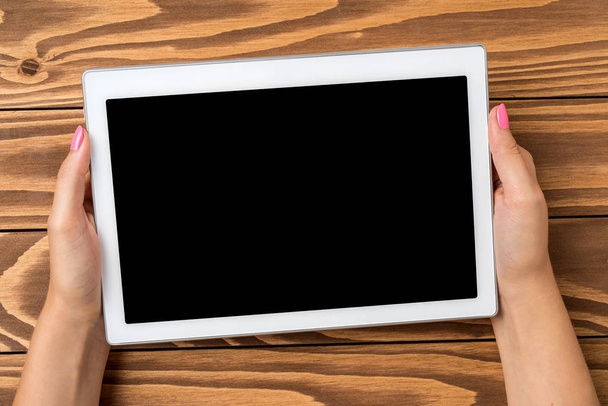 Mujer sosteniendo tableta digital sobre mesa de madera
. - Foto, Imagen