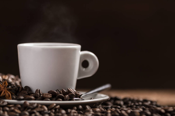 Крупним планом біла чашка гарячої кави та кавових зерен на чорному фоні
 - Фото, зображення