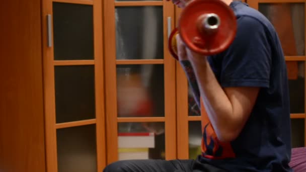 The man lifts the dumbbell, shakes hands in the home - Footage, Video