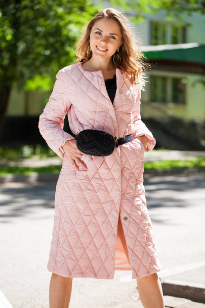 Portrait of a young beautiful brunette woman in pink coat in spring street - Foto, Bild