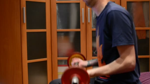 The man lifts the dumbbell, shakes hands in the home - Video