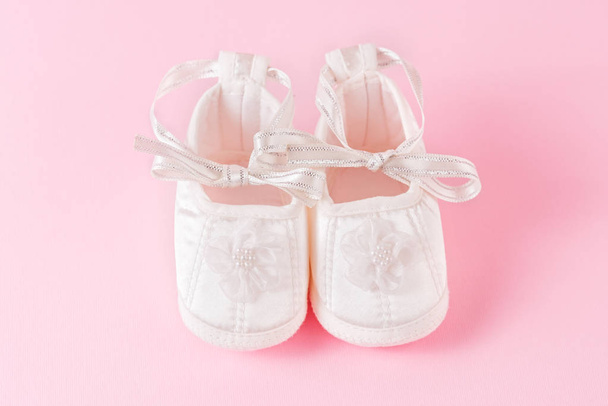 White baby shoes on pink background. A pair of baby shoes. It`s a girl! - Photo, Image
