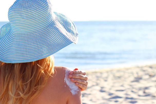 slunce s opalovací krém na dívčí rameno proti moři - Fotografie, Obrázek