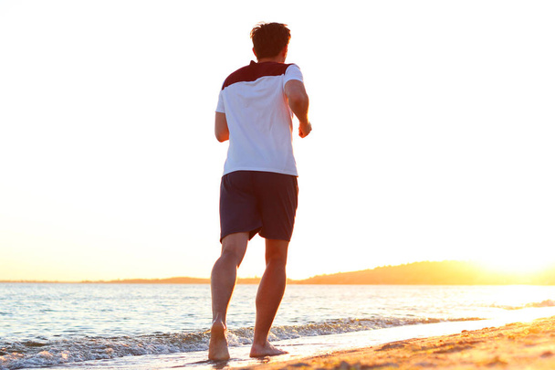 хлопець біжить уздовж узбережжя проти заходу сонця
 - Фото, зображення