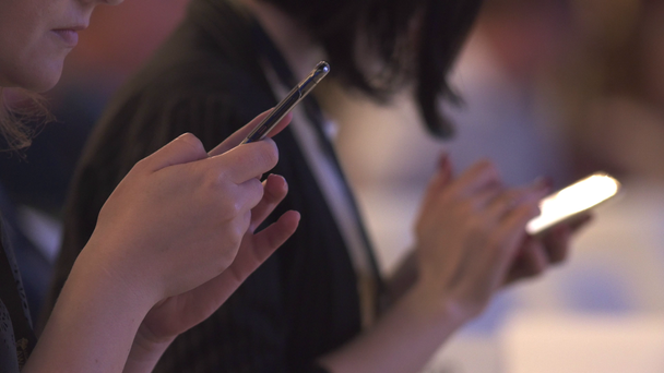 Manos de mujeres escribiendo en sus teléfonos en una conferencia
 - Metraje, vídeo