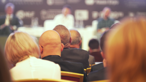 Багато людей сидять у великому залі на бізнес-конференції
 - Кадри, відео
