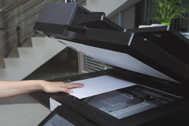 woman hand putting a sheet of paper into a copying device in the office - Foto, immagini