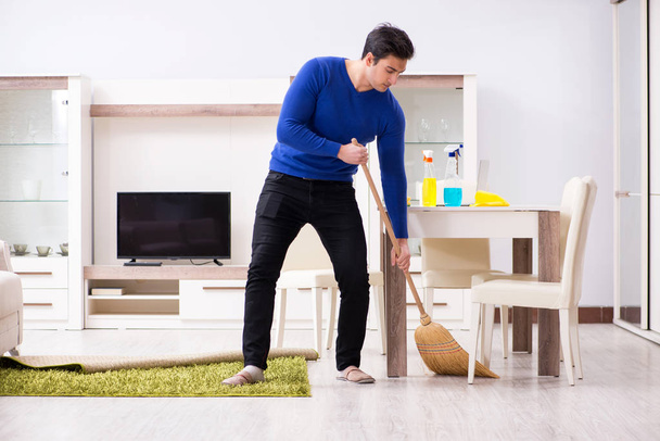Joven hombre limpieza piso con escoba - Foto, imagen