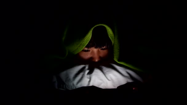 Nuori aasialainen tyttö katsomassa online-sisältöä älypuhelimellaan ja piilossa peiton alla yöllä makuuhuoneessa
. - Materiaali, video