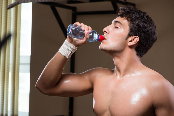 Thirsty man drinking water in sports gym - 写真・画像