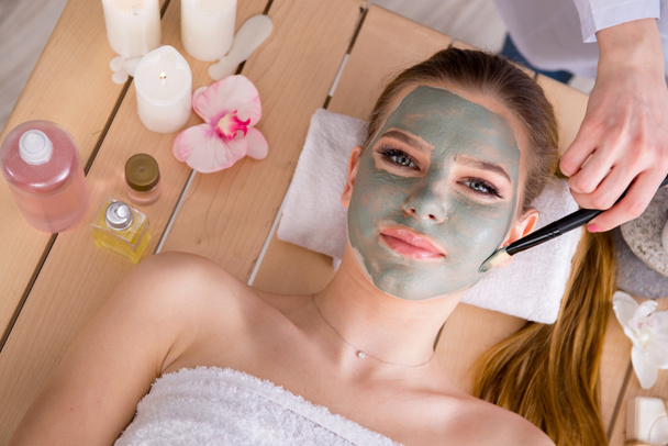 Jonge vrouw in spa gezondheid concept met gezicht masker - Foto, afbeelding