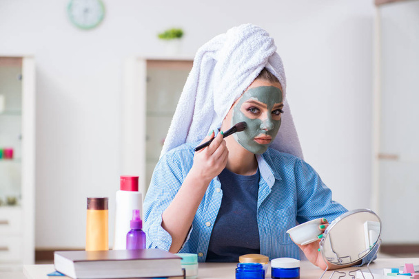 Frau trägt Tonmaske zu Hause mit Pinsel auf - Foto, Bild
