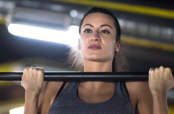 young muscular woman doing pull ups on the horizontal bar as part of Cross fitness Training - 写真・画像