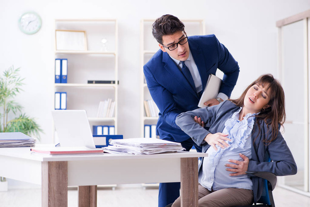 Hamile kadın ofiste debeleniyor ve iş arkadaşı oluyor. - Fotoğraf, Görsel