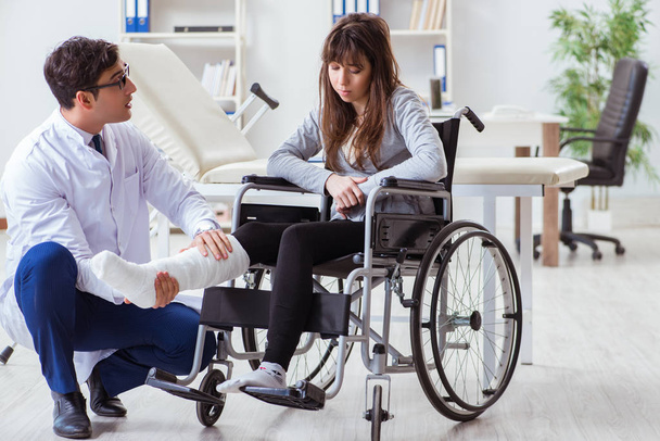 Médico masculino examinando paciente femenino en silla de ruedas - Foto, Imagen