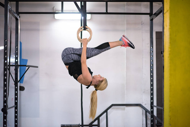 young athletic woman working out on gymnastic rings at the cross fitness gym - Fotoğraf, Görsel