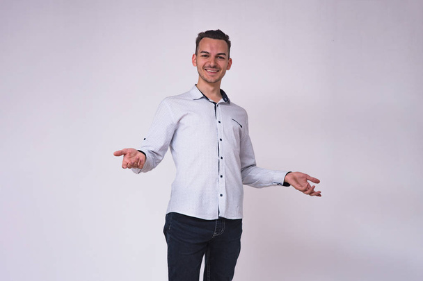 portrait of a cute young brunette man on a white background in different poses with different emotions. He stands directly in front of the camera and shows different emotions - Zdjęcie, obraz