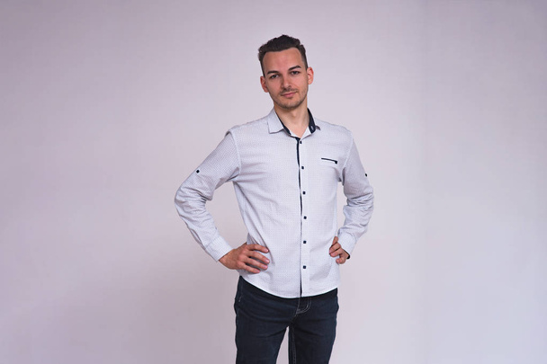 portrait of a cute young brunette man on a white background in different poses with different emotions. He stands directly in front of the camera and shows different emotions - Φωτογραφία, εικόνα