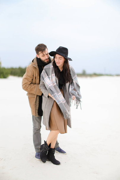 Happy female person and man with beard wearing coats and scarfs standing in winter snow background. - Photo, Image