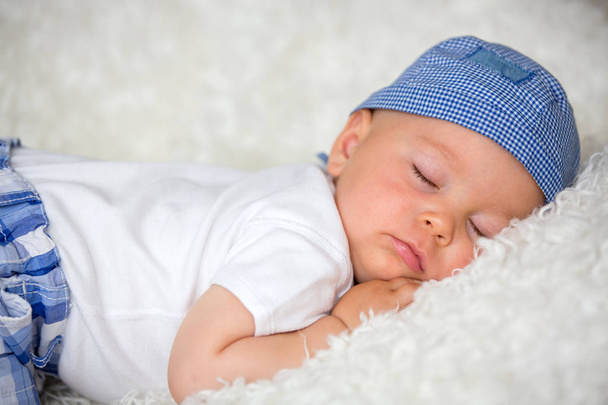 Cute baby boy, sleeping in bed with hat at home - Foto, imagen