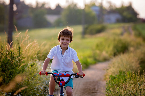 Sporty children, boy brothers, riding bikes on a rural landscape together on sunset - Photo, Image
