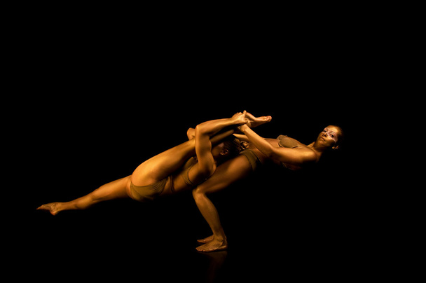Two acrobatic girl toned in gold - Foto, imagen