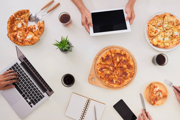 The office staff eat pizza and drink coffee in the business office. They have a break in their work. They are resting. - Foto, Imagem