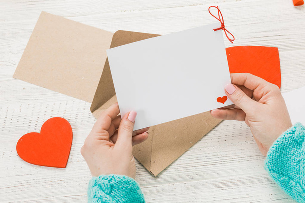 Hand eines Mädchens, das am Valentinstag Liebesbriefe schreibt. Handgefertigte Postkarte mit roter Herzfigur. 14 februar feiertag. Valentinstag-Konzept mit Kopierraum. - Foto, Bild