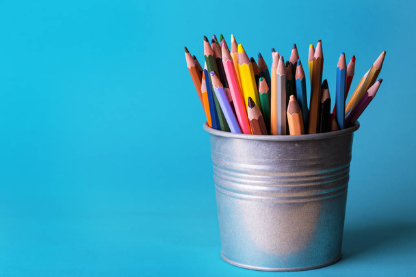 bucket with colorful pencils on a blue backgroun - Foto, afbeelding