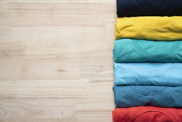 close up of rolled colorful clothes on the wooden table background - Photo, Image