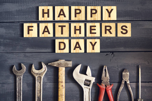 Happy Father's Day inscription on wooden cubes with working tools on a wooden background. Greetings and gifts.Holidays. - Valokuva, kuva