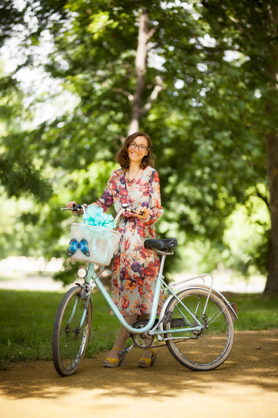 girl with vintage bicycle on a road in the park - Photo, Image
