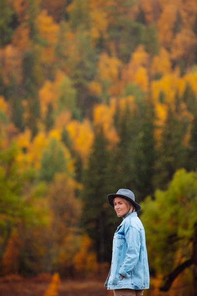Beautiful young woman in hat on autumn forest background. Landscape in autumn.  - Foto, immagini