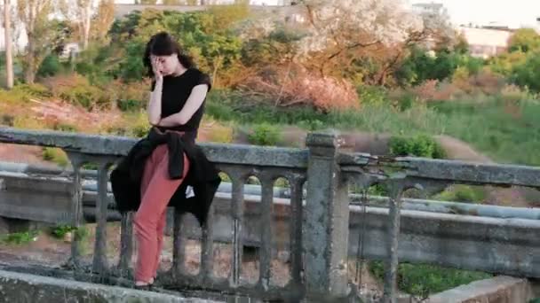 A view from right to left of a sad woman, standing on a bridge, who sadly covers her face with hands and starts - Footage, Video