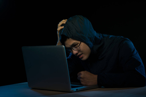 Hacker em um escuro encapuzado sentado na frente de um caderno. Ataque de privacidade
 - Foto, Imagem