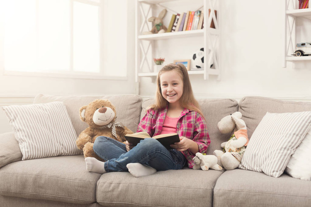 Happy little child reading book for her teddy bear - Φωτογραφία, εικόνα