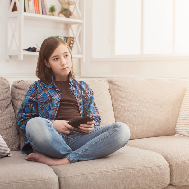 Joven chica seria viendo la televisión con control remoto
 - Foto, imagen