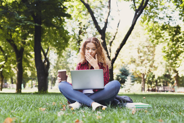 Casual yllättynyt tyttö kannettavan kaupungin puistossa. Nuori freelancer työskentelee tietokoneella ulkona. Teknologia, viestintä, koulutus ja etätyö, kopiotila
 - Valokuva, kuva