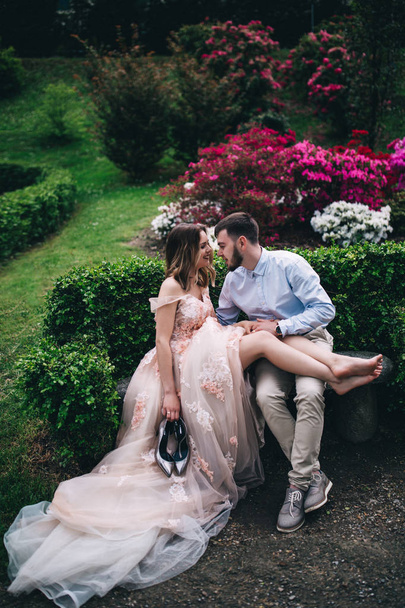 Walking newlyweds in nature. The bride and groom rest on the bench. - Foto, afbeelding