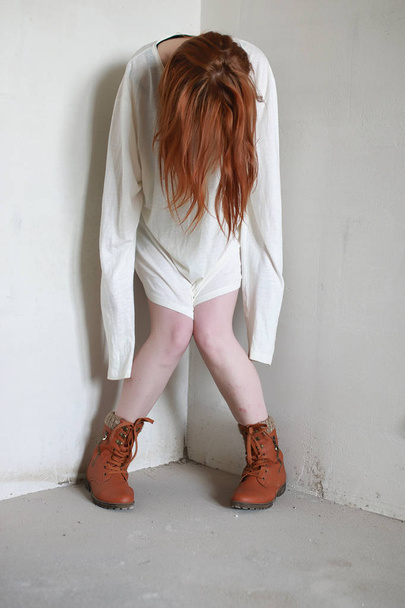 A girl with red hair in a shirt. Domestic violence and sacrifice. Girl with a sick psyche. - Foto, Imagem