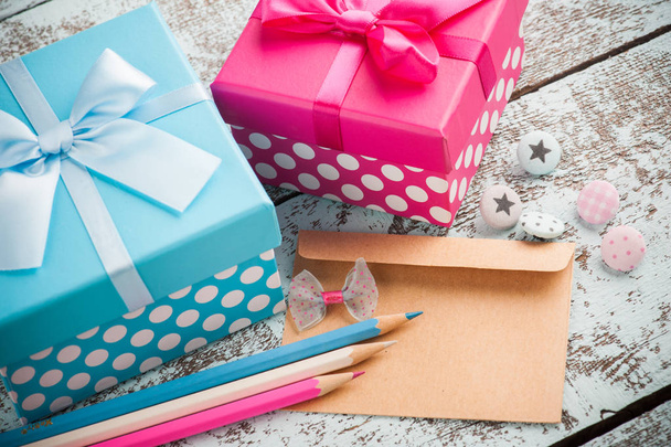 Пустой конверт с голубыми и розовыми карандашами, пуговицами, подарочными коробками. День рождения
 - Фото, изображение